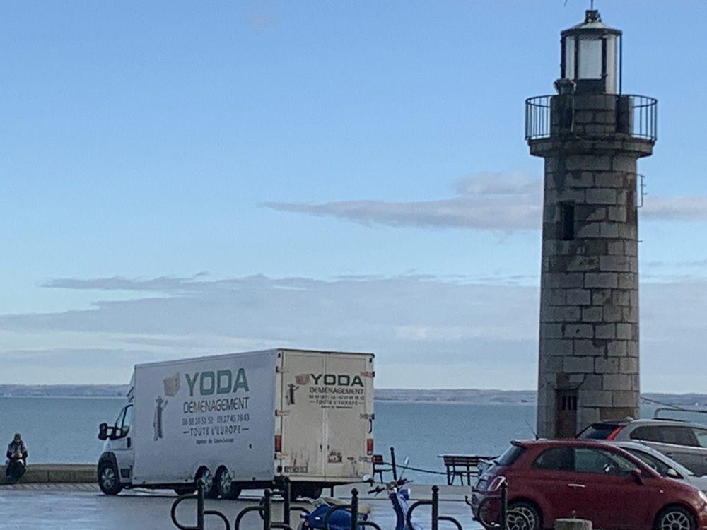 Un camion de déménagement sur la digue à côté d'un phare